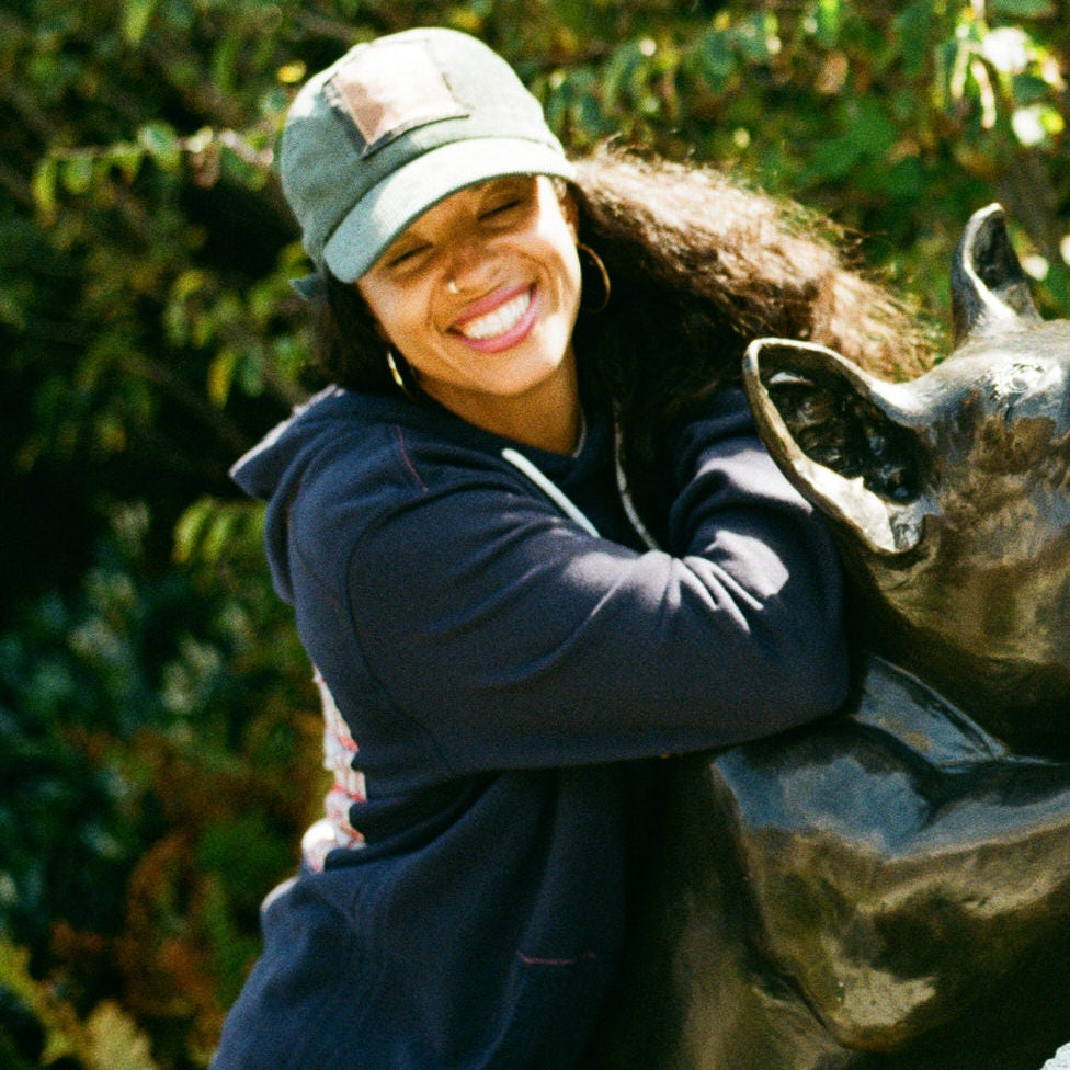 Two people posing with a statue outdoors.