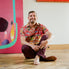 Man sitting on a wooden floor in front of colorful artwork