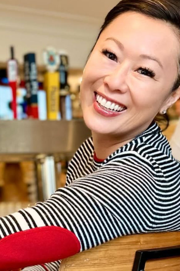 Woman wearing a black and white striped Daniel Hammond cashmere sweater with red sleeves in an indoor setting.